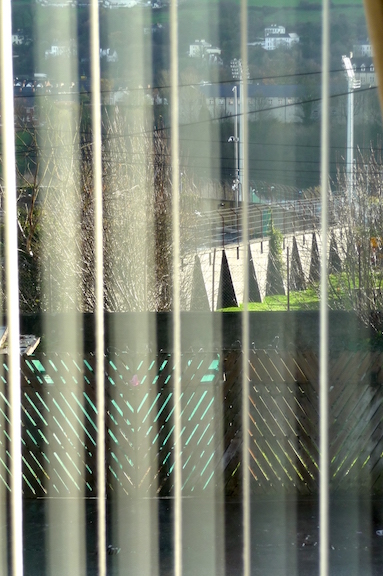 Day of the Rat (2010)&amp;nbsp;1800 x 1200 x 40mm. Ultra slim LED lightbox, Duratran '...In&amp;nbsp;Day of the Rat, a photographic image presents the view through the blinds of a window, overlooking an imposing concrete bunker. At a formal level, one notes the voyeuristic arrangement of the scene, the artist's gaze from the periphery, from the inside of the house, onto the landscape. The anecdotal subtext adds another layer, however, re-visiting the political history of Northern Ireland from a contemporary, post-Troubles perspective. Morris had been asked to sort out a dead rat, decomposing underneath the floorboards of his mother's house. Having called in professional exterminators, who were engaged in cutting holes in the&amp;nbsp;floor while trying to 'sniff out' the corpse, the artist and his family retreated to the upstairs bedroom. Here, his eye was caught by the glare of sunlight through the window and a glimpse through the shutters of a cemetery outside. For Morris, the building's stark exterior, brutalist architecture and nearby floodlights recalled a prison camp and it is this (un) intentional misreading that can be seen to bridge the two divides of his practice. The correspondence between cemetery and floorboards, the artist sequestered in his mother's bedroom while 'interpreting' the building as a prison, the uncanny charge of the past rushing into the present; through these accidents, one infers the legacy of the Troubles. It is Morris' attunement to such connections, and his ability to re-assemble and re-create that experience, that offers another, subtler reading. It is this anecdote that resists the overall, objective meaning and that states, without apology: &amp;ldquo;I guess you had to be there.&amp;rdquo;&amp;nbsp;(text extract&amp;nbsp;&amp;lsquo;Practicing everyday life&amp;rsquo; Chris Clarke,&amp;nbsp;This Then, Locky Morris, Catalogue 2010 )